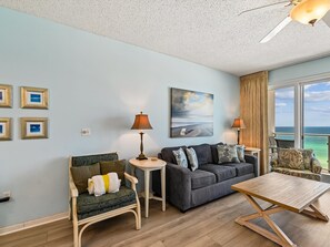 Ein Zimmer mit Sofa, Ohrensessel, Couchtisch und einem Kunstwerk an der Wand.
