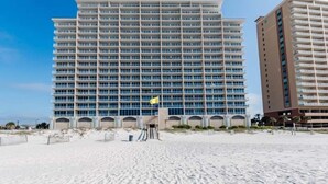 A large hotel with multiple floors and balconies, situated on a sandy beach with clear skies. - Gulf Front Condo with Stunning View and Resort Amenities (Gulf Shores)