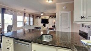 A kitchen with a granite countertop, white cabinetry, and a built-in dishwasher. - Beach Condo, Lake Views! (Orange Beach)