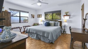 A bedroom with a bed, a ceiling fan, a window, a lamp, and a wooden table. - 60-Acre Retreat w/ Hot Tub, Firepit & Pet-Friendly! (Wimberley)