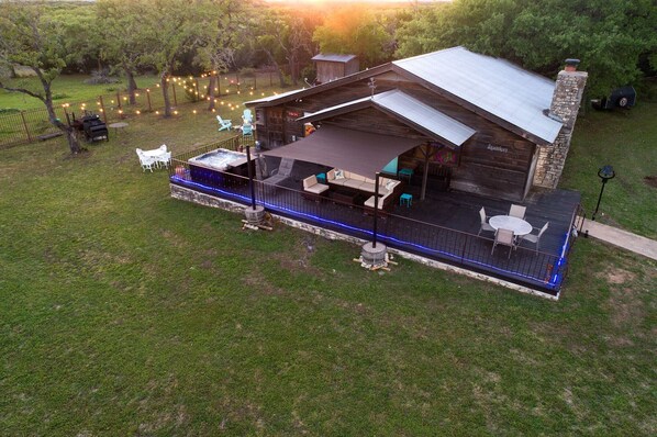 A rustic cabin with a covered patio, outdoor seating, and a barbecue area.