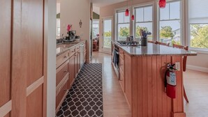Une cuisine moderne avec des meubles en bois, un grand îlot central et des luminaires suspendus.