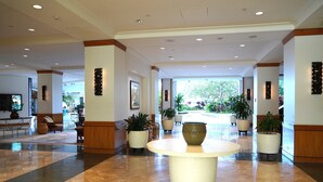 A spacious lobby with a central round table, potted plants, and a reception desk. - New Aloha Waikiki Ilikai Hotel Condo Free Parking (Honolulu)