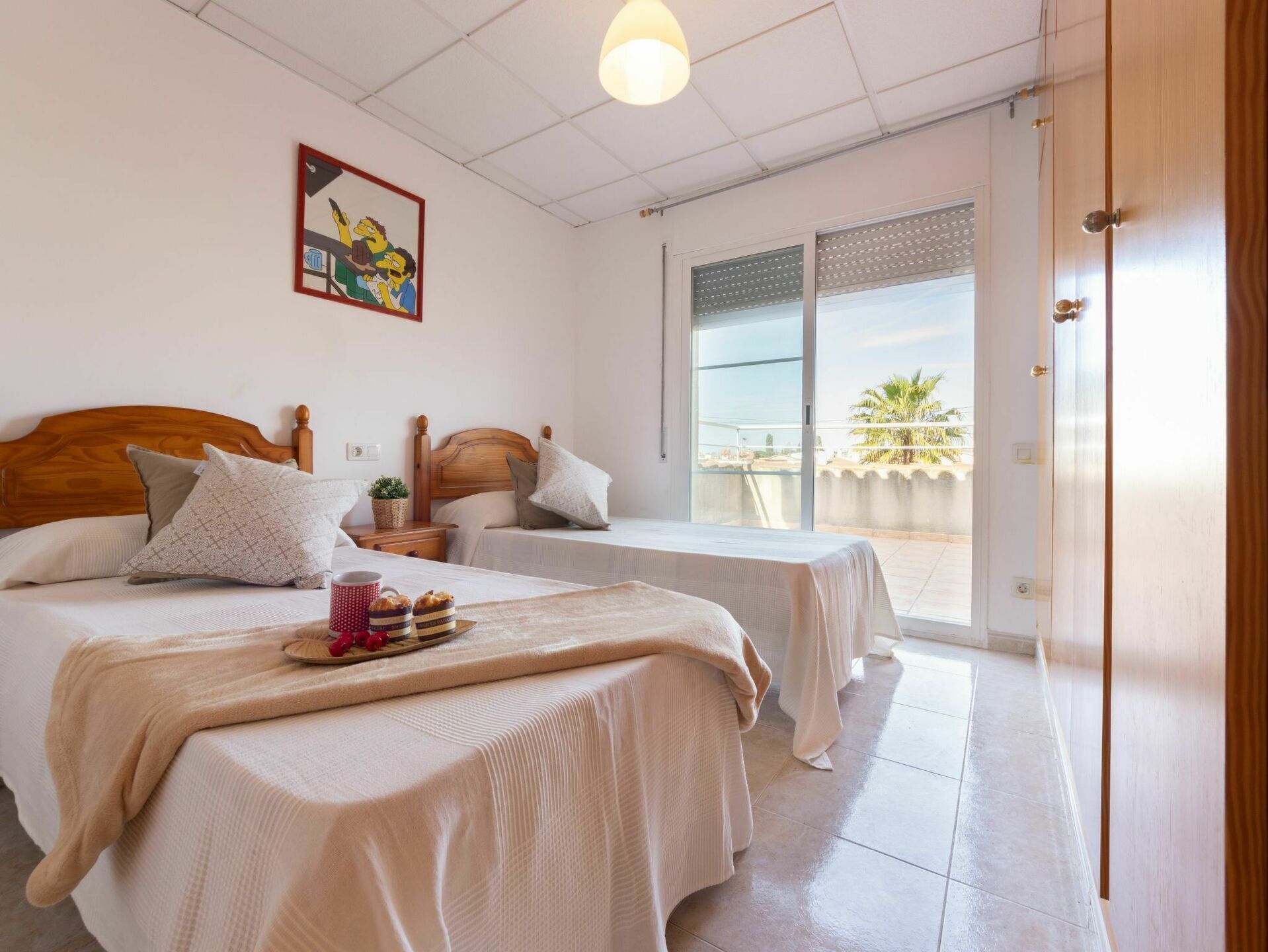 Une chambre d’hôtel avec deux lits, un balcon donnant sur un beau paysage et un tableau accroché au mur.