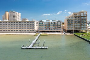 Un hotel sul lungomare con numerosi balconi, un molo e una vista chiara sull'acqua.