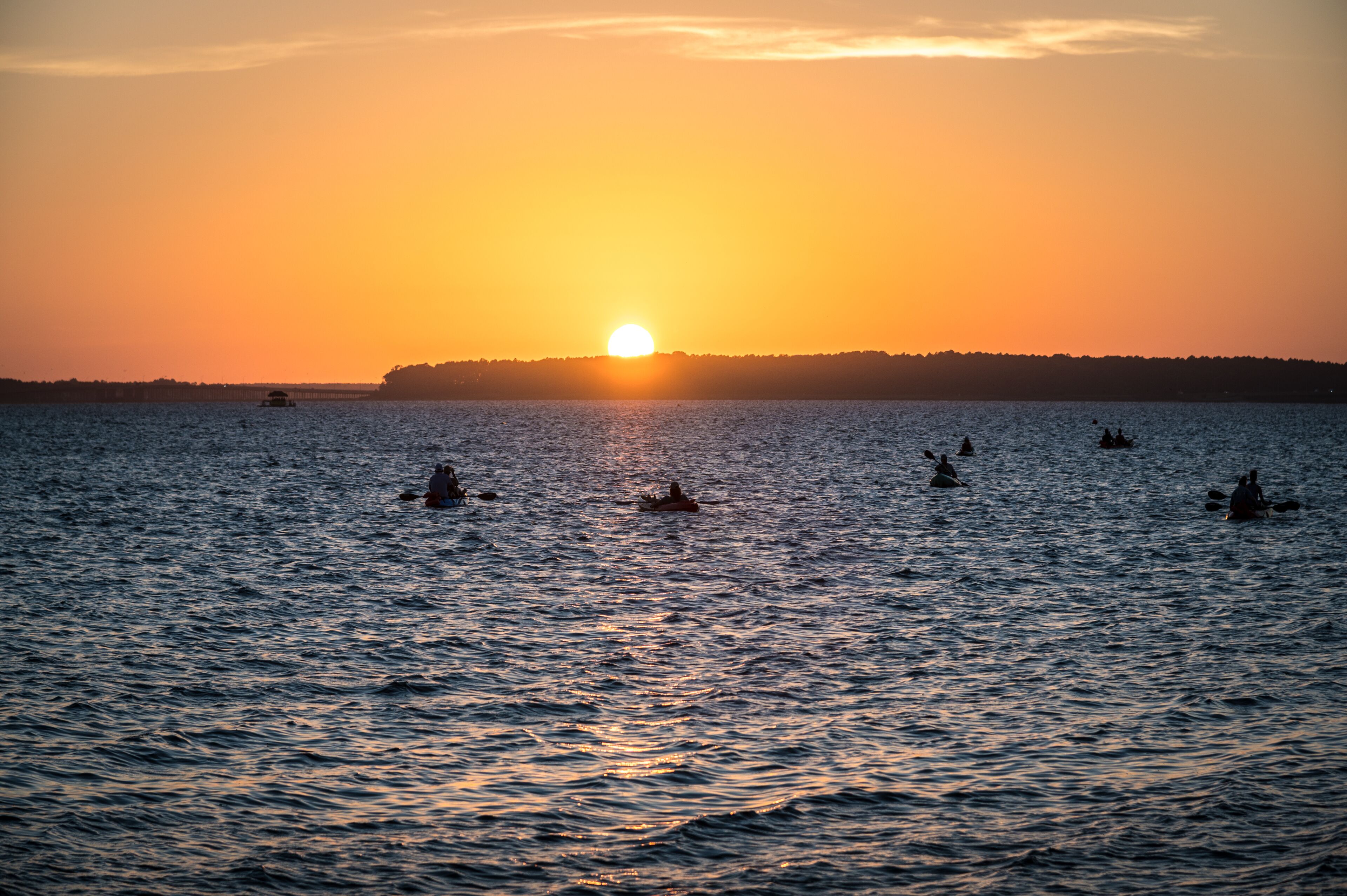 Un atardecer sobre un cuerpo de agua tranquilo, con varias embarcaciones.
