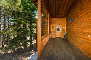 Step into this cozy cabin, featuring a covered porch with a wooden railing and a warm inviting interior.