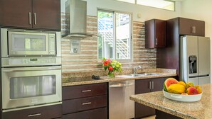 Una cocina moderna con electrodomésticos de acero inoxidable, encimera de granito y ventana con vistas a zonas verdes.