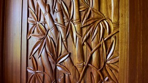 A wooden panel with intricate carvings of bamboo leaves and stems.