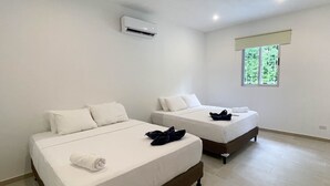 Two single beds with white linens, a window with a view of greenery, and an air conditioning unit on the wall. - Parrot-dise Perch, 3BD, Heart of Manuel Antonio (Quepos)