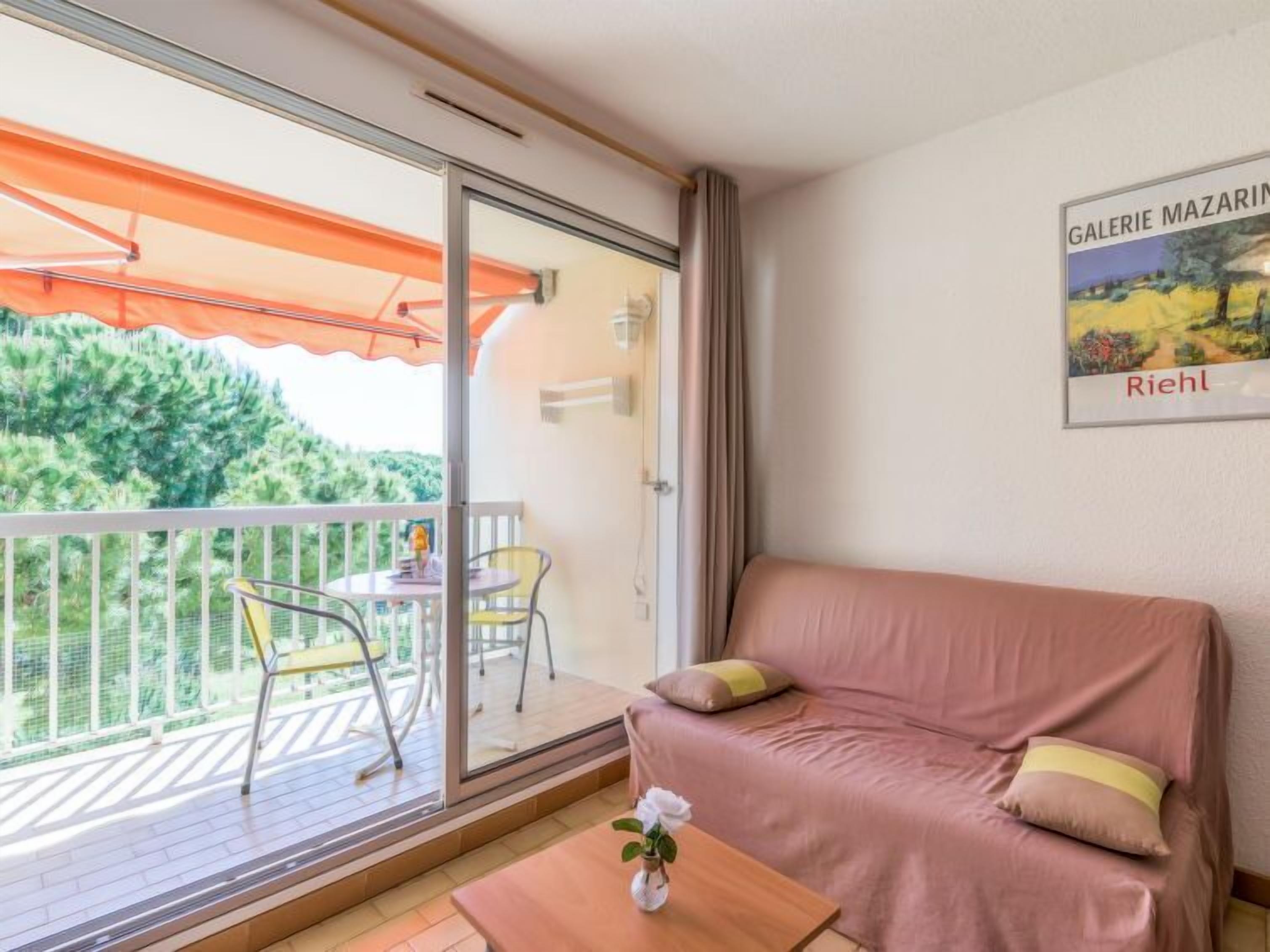 A balcony with a table and chairs, a sofa, and a painting on the wall.