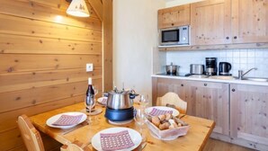 A wooden interior with a dining table set for two, a microwave, and a coffee maker.