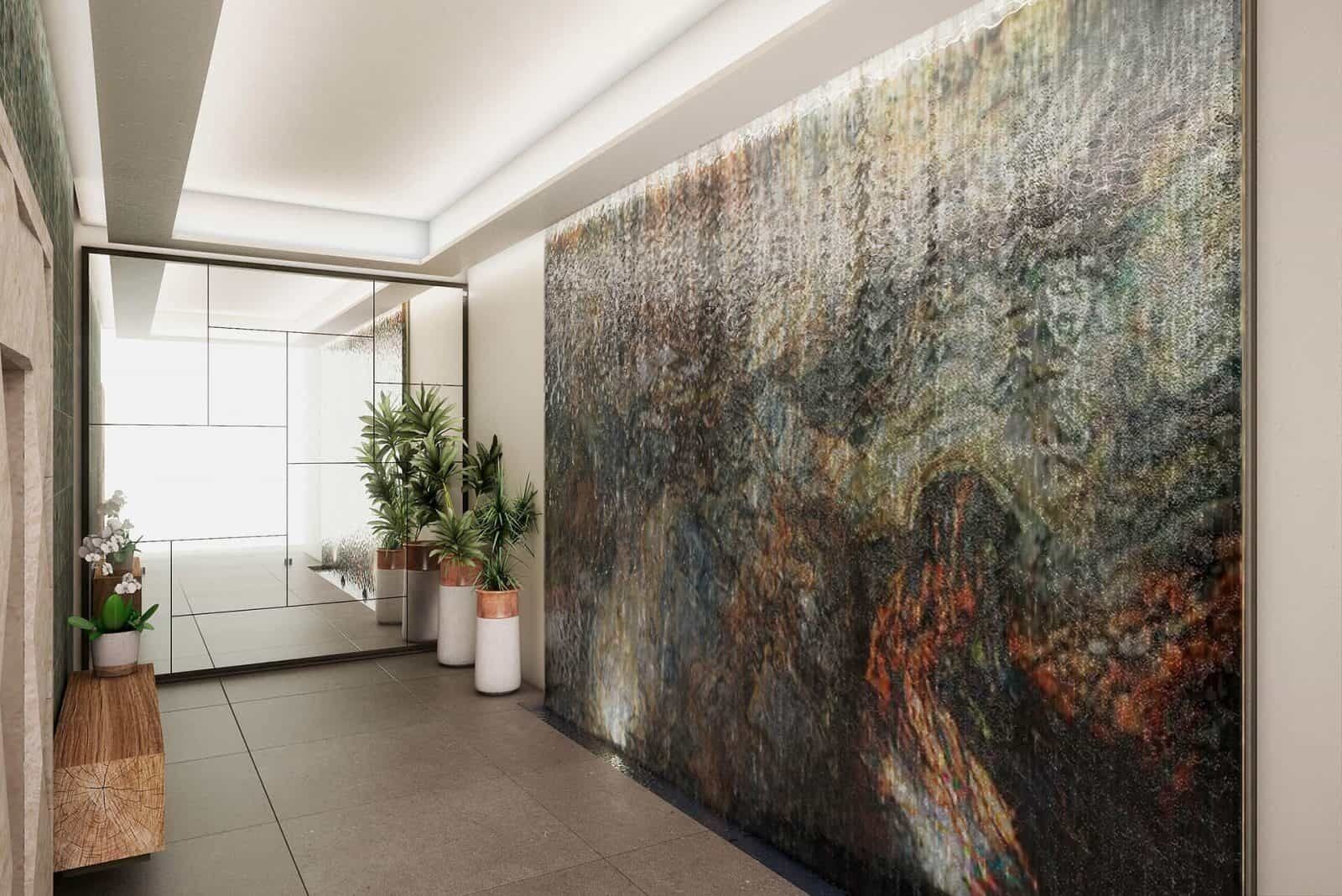 A modern hallway with a large abstract painting on the wall, potted plants, and a glass door leading to another room.