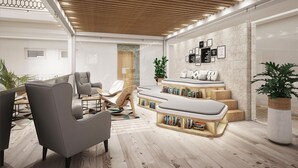 Een moderne woonkamer met een houten plafond, een inbouwkast en een zithoek met een grijze bank en fauteuils.