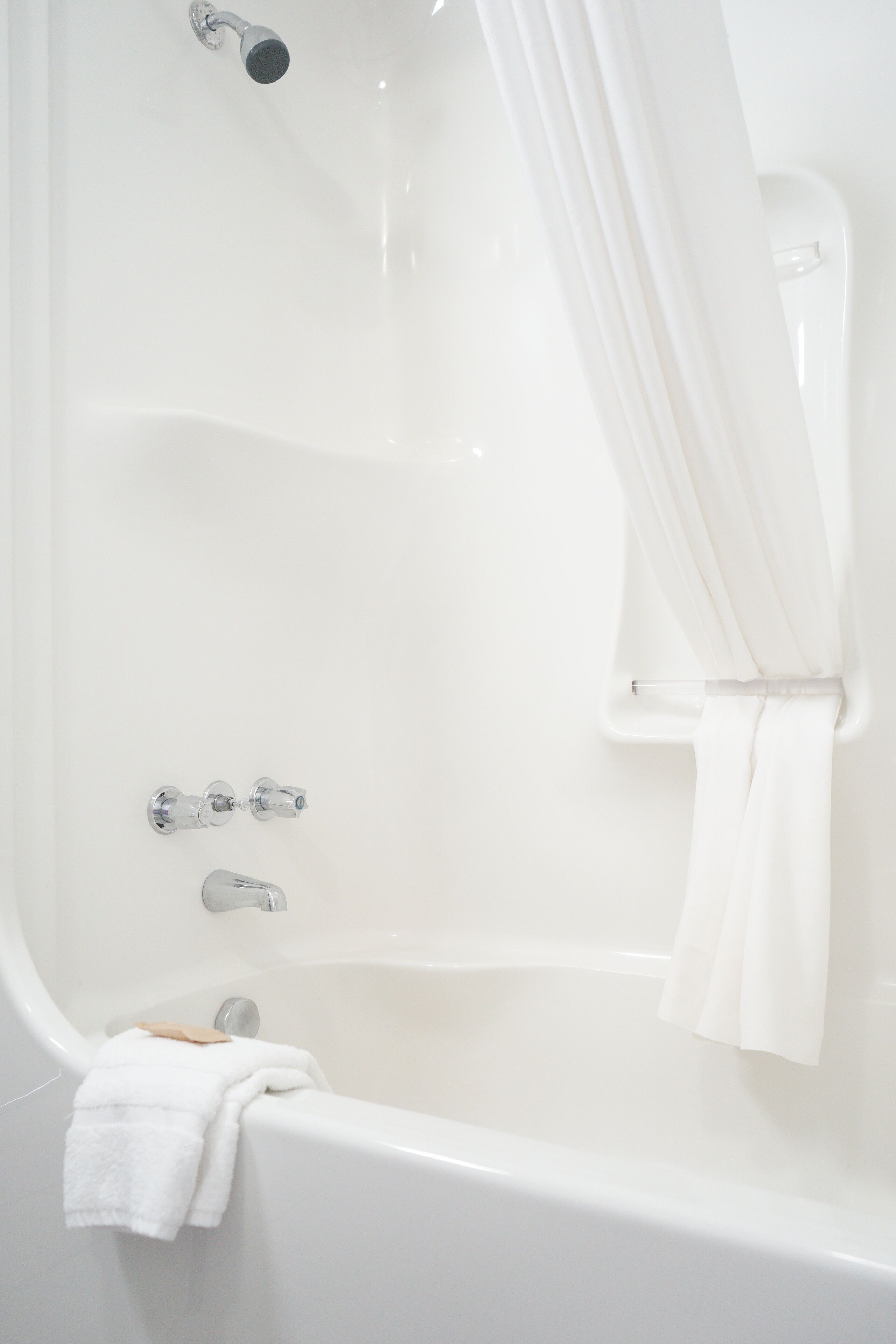 Une baignoire blanche avec un pommeau de douche, une serviette et un porte-savon.
