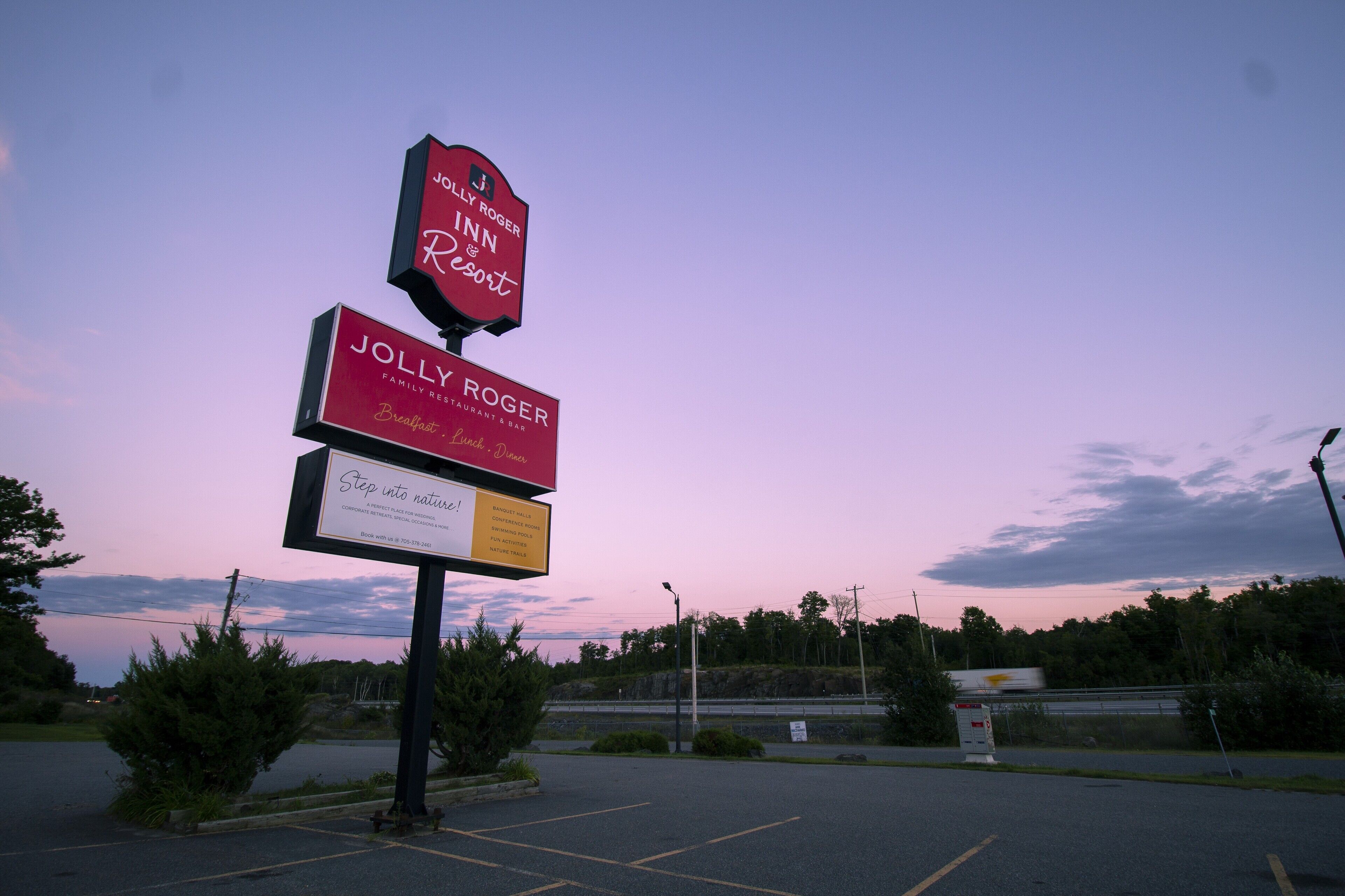 A Jolly Roger Inn & Resort sign with a family restaurant and bar, and a parking lot with a clear sky.