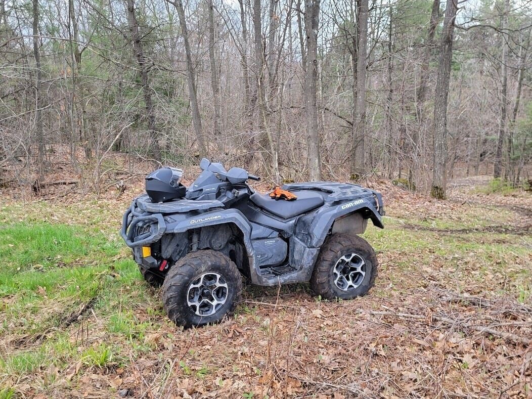 Een zwarte offroad-voertuig met een groot reservewiel op de achterkant, geparkeerd in een bebost gebied.