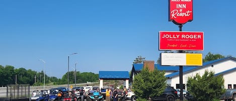 A Jolly Roger Inn & Resort with a clear blue sky, a parking area with ATVs, and a building with a blue roof.