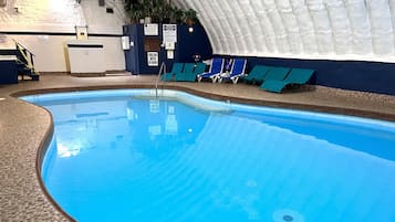 Una piscina interior con suelo de baldosas, un trampolín y varias sillas de descanso.