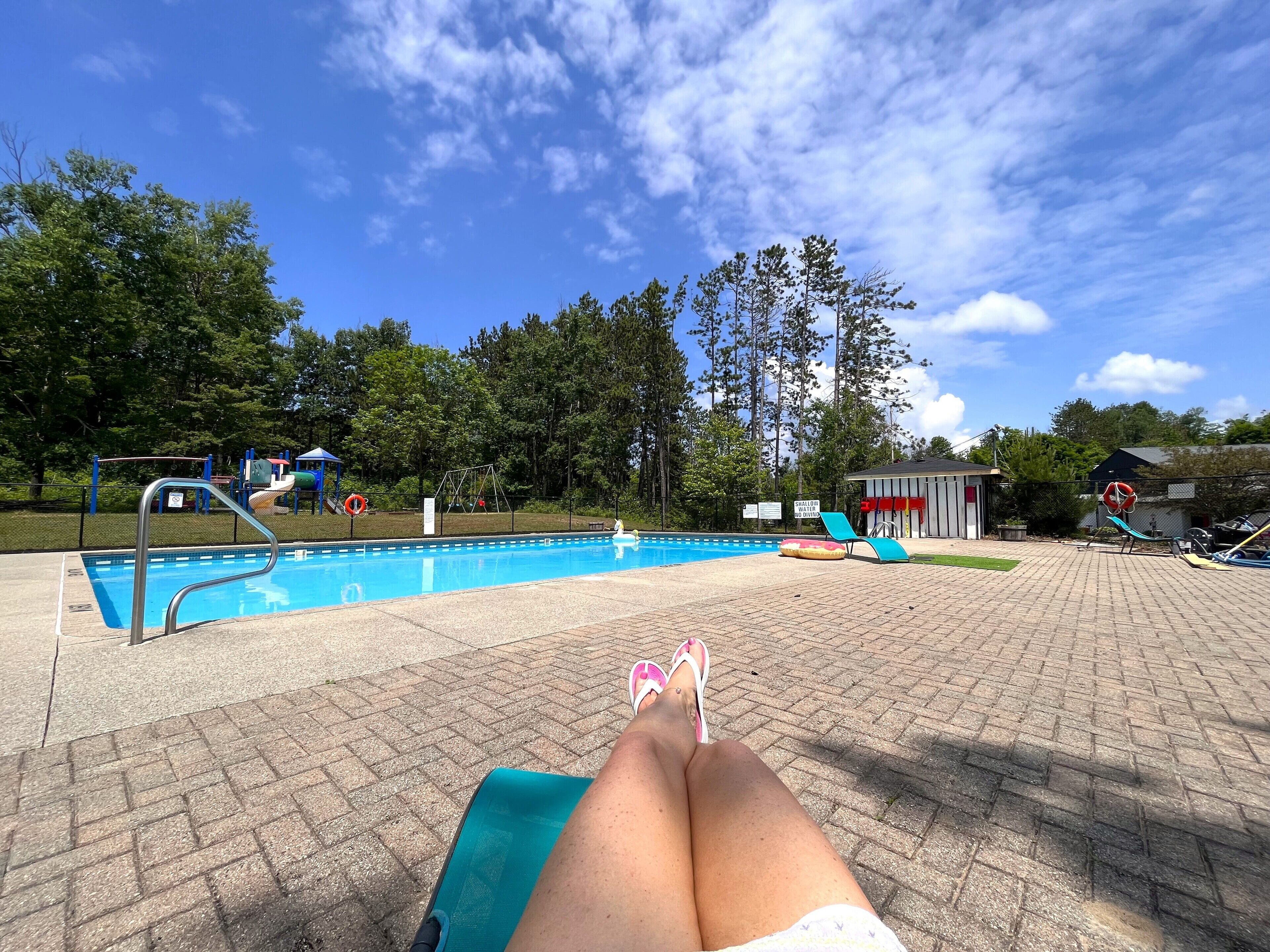 Una piscina amb tobogan i un senyal de precaució per aigua poc profunda.