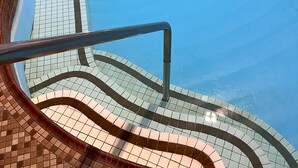 A view of a swimming pool with tiled steps leading down to the water. - Jolly Roger Inn & Resort (Seguin)