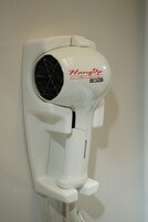 Un sèche-cheveux blanc, fixé au mur, sur lequel on peut voir la marque « HangUp » et le modèle « Andis ».