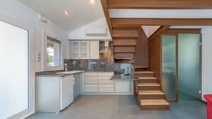 Een moderne keuken met een ingebouwde kookplaat, witte kasten en een houten trap.