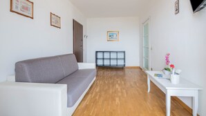 Una sala de estar con un sofá, una mesa blanca con un florero y un radiador.