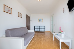 A living room with a sofa, a white table with a vase, and a radiator.