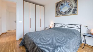 Un dormitorio con cama, mesita de noche, una obra de arte en la pared y armario.