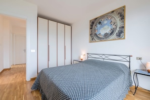 A bedroom with a bed, a nightstand, a wall-mounted artwork, and a wardrobe.