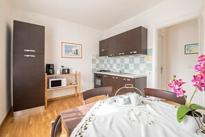 A compact kitchen with dark cabinets, a microwave, and a small dining area with a table set for two.