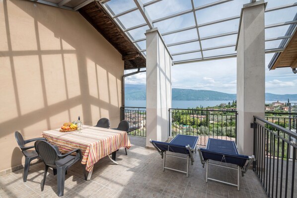 A balcony with a table, chairs, and a ping pong table, overlooking a scenic view.