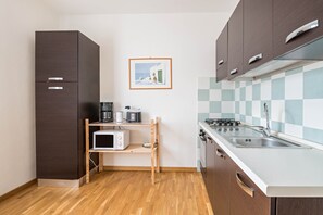 A compact kitchen with a microwave, stove, and sink.