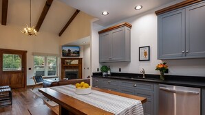 A modern kitchen with grey cabinets, a wooden dining table with a striped tablecloth, and a built-in dishwasher.