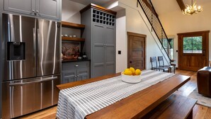 A modern kitchen with stainless steel appliances, a wooden dining table, and a staircase leading to another level.