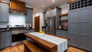 A modern kitchen with grey cabinets, stainless steel appliances, and a wooden bench.