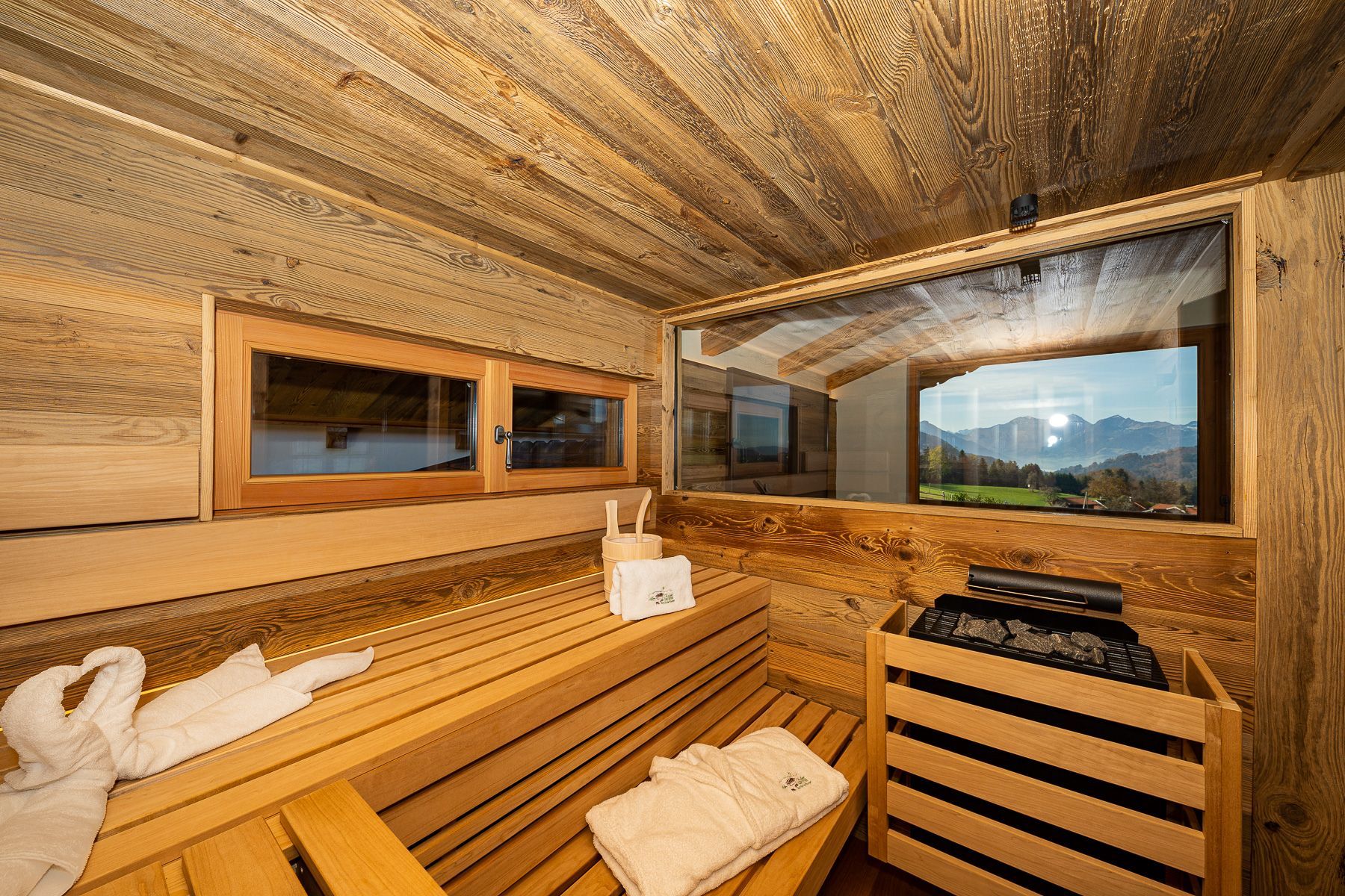 Een houten sauna met banken, handdoeken en een sauna-oven.