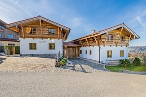 Ein traditionelles Chalet im Alpenstil mit Kieseingang, Holzbalkonen und freiem Blick auf die umliegende Landschaft.
