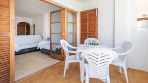 A room with a bed, a table with chairs, and a sliding door leading to another room. - Holiday Apartment "Carabela Greco 139" Near the Beach with Sea Views (Alcudia)