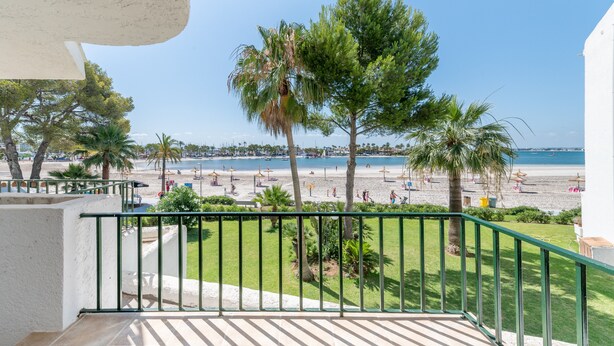 A balcony with a view of a beach, palm trees, and a clear sky. - Holiday Apartment "Carabela Greco 139" Near the Beach with Sea Views (Alcudia)