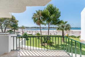 A balcony with a view of a beach, palm trees, and a clear sky.