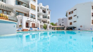 A swimming pool with lounge chairs, white buildings with balconies, and a clear sky. - Holiday Apartment "Carabela Greco 139" Near the Beach with Sea Views (Alcudia)