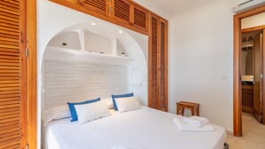 A bedroom with a bed, wooden shutters, and a small table. - Holiday Apartment "Carabela Greco 139" Near the Beach with Sea Views (Alcudia)