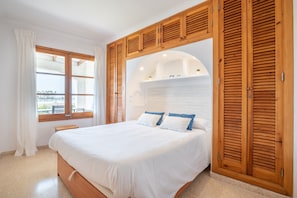 Une chambre à coucher avec un lit, une armoire en bois et une fenêtre avec des rideaux.