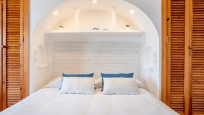 A bedroom with a white bed, two pillows, a wooden headboard, and a small shelf with decorative items. - Vacation Apartment “Carabela Dali 113” Close to the Beach with Sea View and Pool (Alcudia)