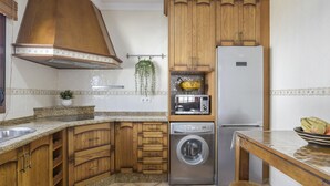 A kitchen with wooden cabinets, a stainless steel refrigerator, a washing machine, and a microwave.