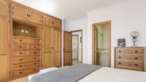 A bedroom with a bed, wooden wardrobe, and a mirror.