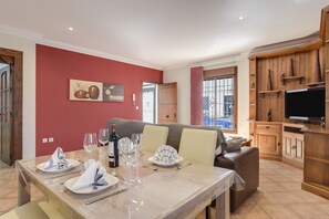A dining area with a table set for four, a sofa, and a TV in the background. - Apartment "Casa Ainhoa" with A/C & Terrace & WIFI (Conil)