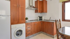Una cucina con mobili in legno, un forno a microonde integrato e una lavatrice.